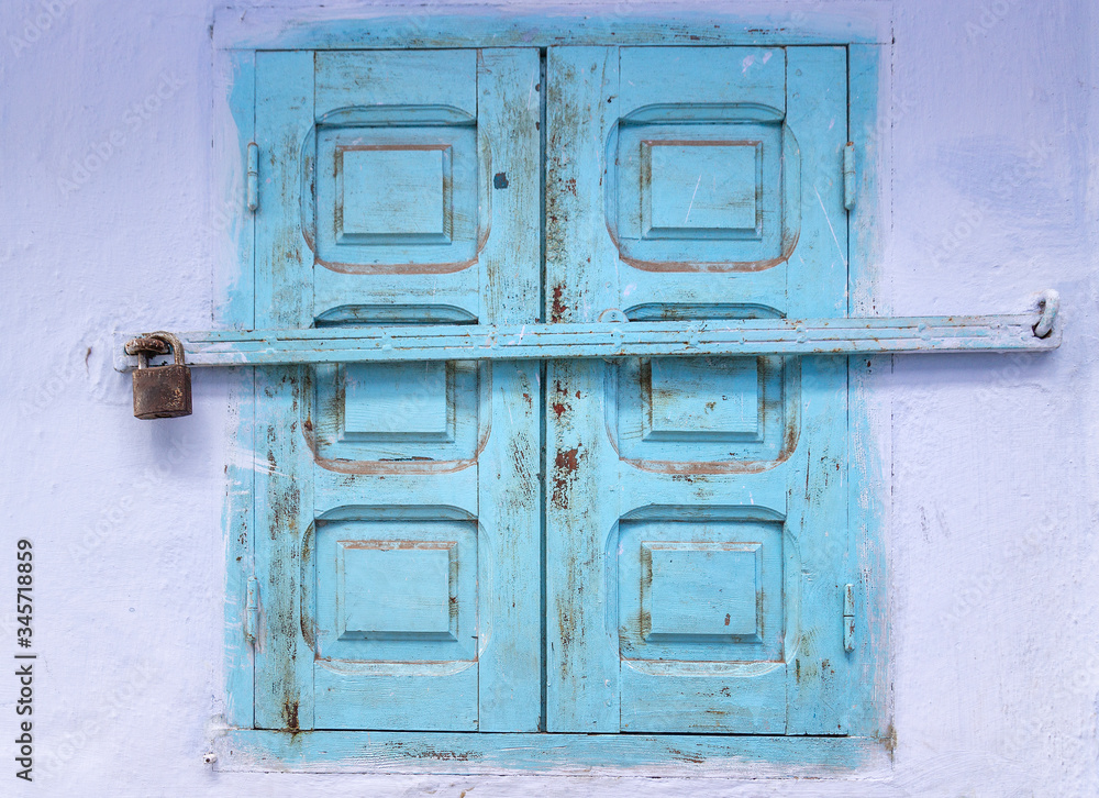 Window with blue wooden shutters closed on padlock. House details in North Africa. Medina of Chefchaouen town, Morocco.