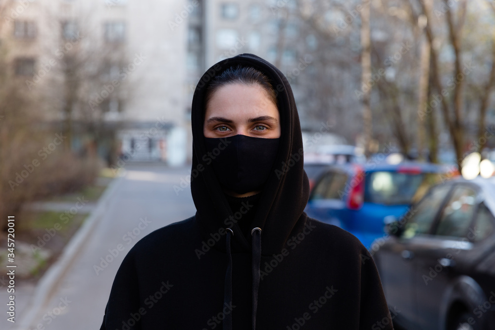 Young woman wearing face mask. Handsome woman in black hoodie wear black medical mask. Pandemic coronavirus covid-19 quarantine period concept. Young woman wearing face mask. Handsome woman in black hoodie wear black medical mask. Pandemic coronavirus covid-19 quarantine period concept.