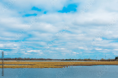 Bank with yellow grass and reflected blue sky in the river water. High contrast of blue and orange.