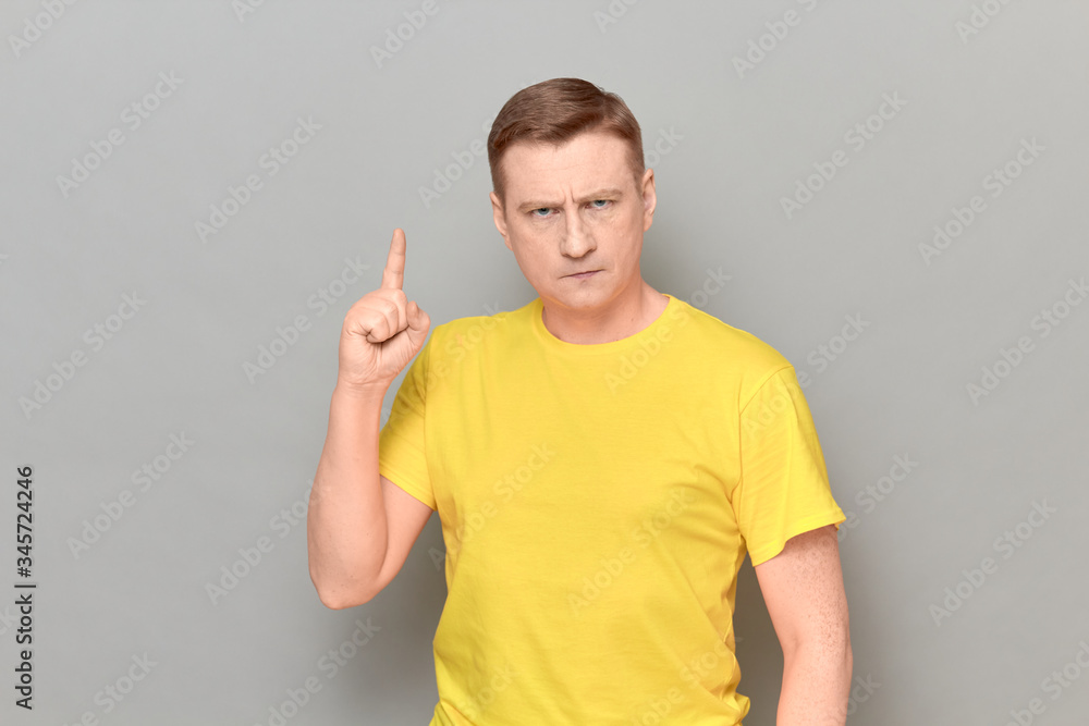 Portrait of serious focused mature man raising index finger Portrait of serious focused mature man raising index finger