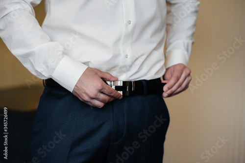 Stylish young man buttoning the cuff links on the sleeves. Style
