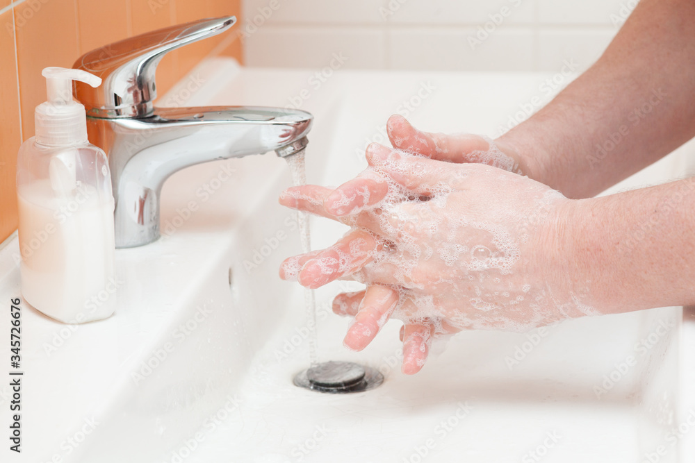 man washes hands with hot water and soap in the bathroom. Personal hygiene, prevention of corona virus infection man washes hands with hot water and soap in the bathroom. Personal hygiene, prevention of corona virus infection