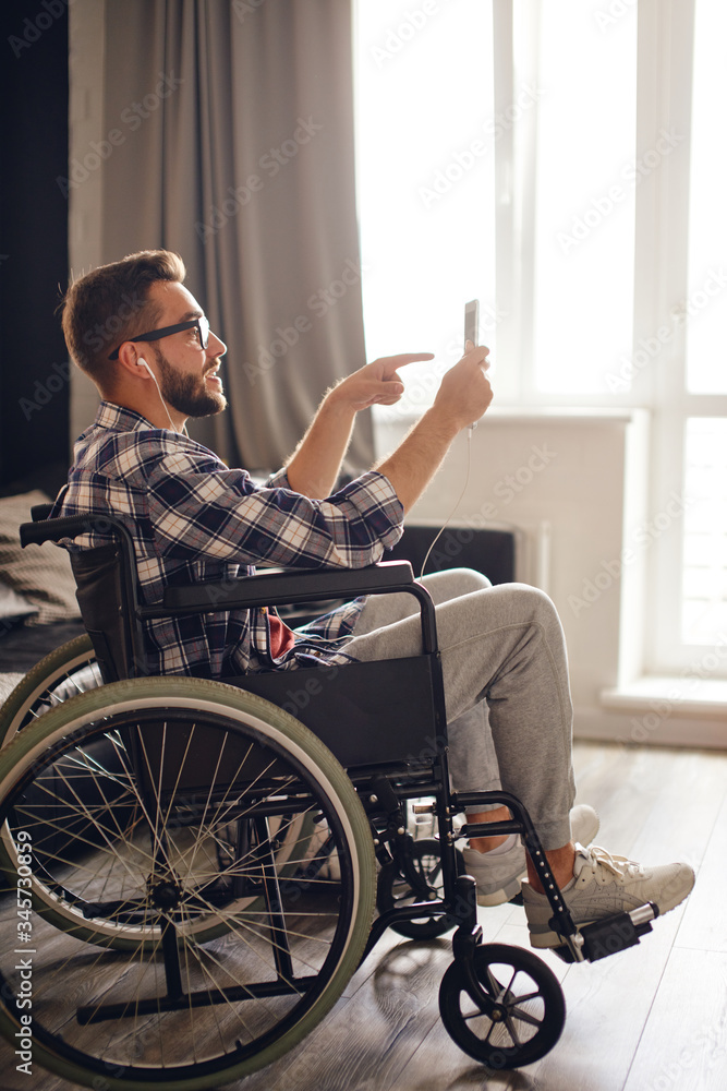 Man in wheelchair pointing finger while chatting on tablet Man in wheelchair pointing finger while chatting on tablet
