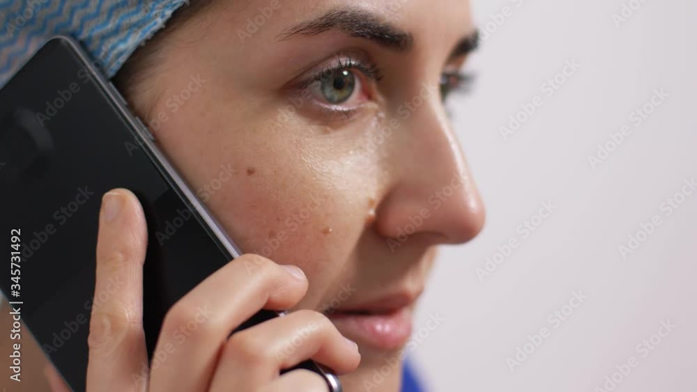 medicine, healthcare and pandemic concept - close up of crying young female doctor or nurse calling on smartphone over grey background medicine, healthcare and pandemic concept - close up of crying young female doctor or nurse calling on smartphone over grey background