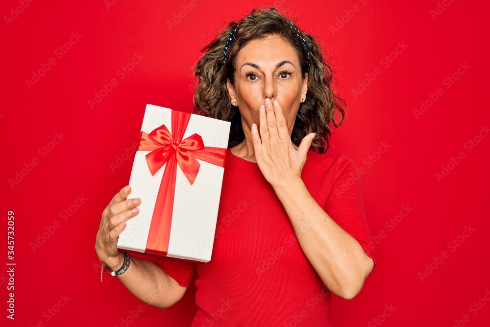 Middle age senior woman holding romantic present box over red isolated background cover mouth with hand shocked with shame for mistake, expression of fear, scared in silence, secret concept Middle age senior woman holding romantic present box over red isolated background cover mouth with hand shocked with shame for mistake, expression of fear, scared in silence, secret concept