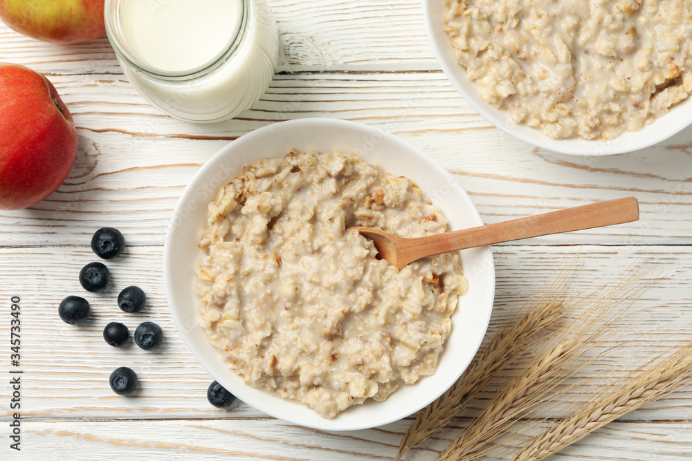 Composition with oatmeal porridge on white wooden background. Cooking breakfast Composition with oatmeal porridge on white wooden background. Cooking breakfast
