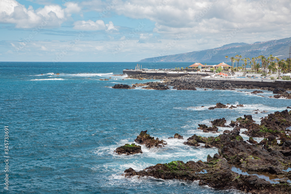 Atlantic ocean and coastline rocks with view of public pools Lagos Martianes. Puerto De La Cruz, Canary Islands, Spain - March 15 2020