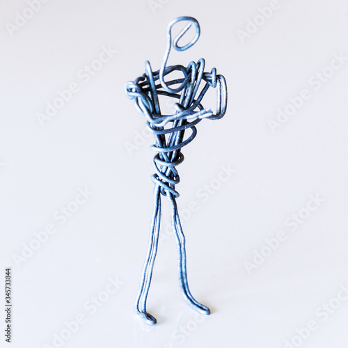 A man of wire stands in a closed position with his hands on his chest, symbolizing failure, aggression, closeness