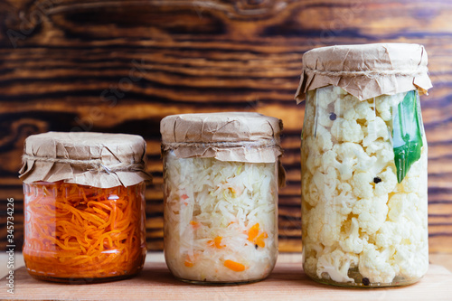 Fermented vegetables cabbage, cauliflower, carrot in glass jar on wood background.