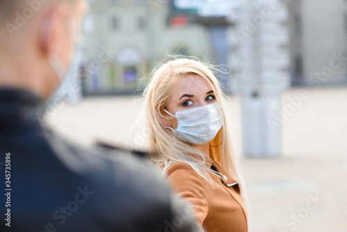 Young couple in masks on city street.