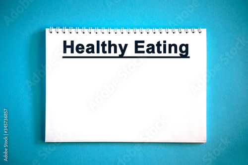 Healthy eating - text on a white notebook on a blue background