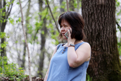 Happy woman talking on mobile phone in a spring forest. Concept of cellular communication on a nature