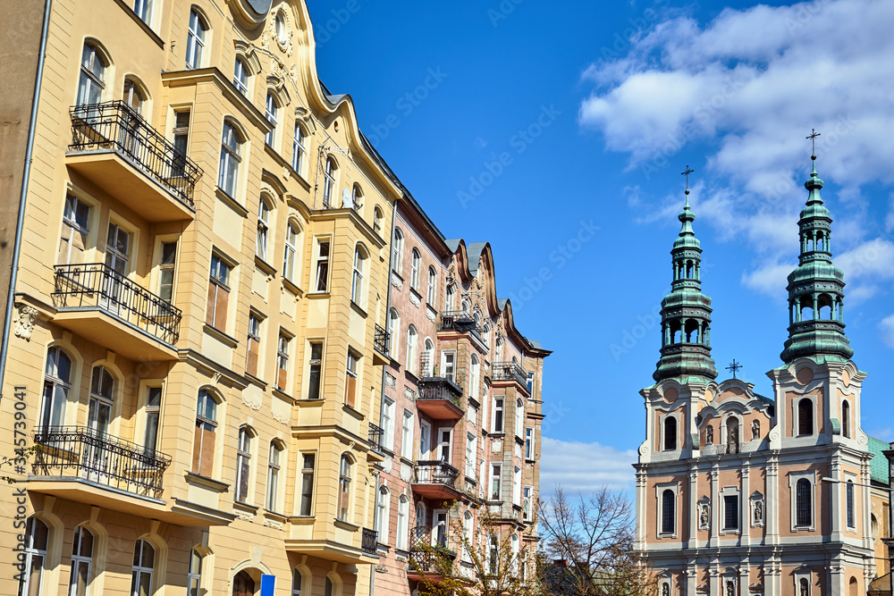 facade of a historic tenement house and belfries of the baroque church in Poznan.