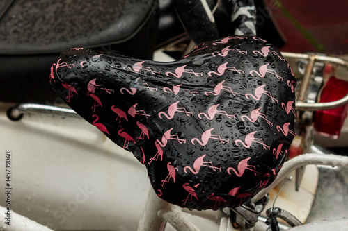 Bicycle seat with drawn rain wetted flamingos. photo