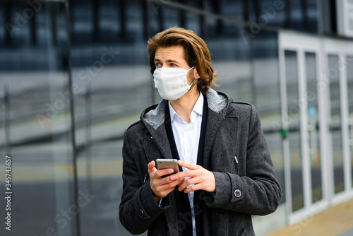 Young man in a medical mask outside, no money, crisis, poverty, hardship. Quarantine, coronavirus, isolation.