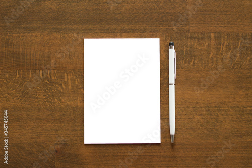 Blank paper and a pen on wooden background. photo