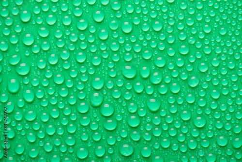 Top above overhead close up view photo of different size bright water drops on the green background