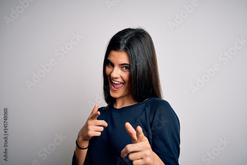 Young beautiful brunette woman wearing casual sweater standing over white background pointing fingers to camera with happy and funny face. Good energy and vibes.