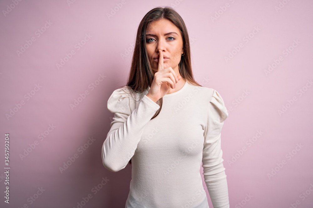 Young beautiful woman with blue eyes wearing casual white t-shirt over pink background asking to be quiet with finger on lips. Silence and secret concept. Young beautiful woman with blue eyes wearing casual white t-shirt over pink background asking to be quiet with finger on lips. Silence and secret concept.