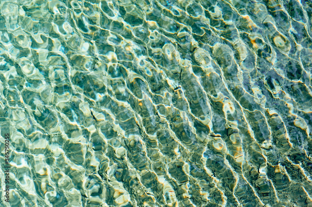 Blurry structure of the water, shimmering in the sun. Cold tones. Blurry structure of the water, shimmering in the sun. Cold tones.