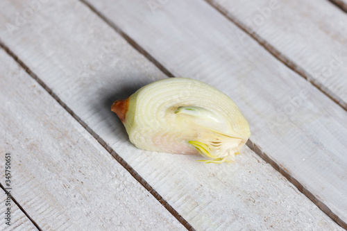 cut quarter of onion with green sprout inside on white wooden table