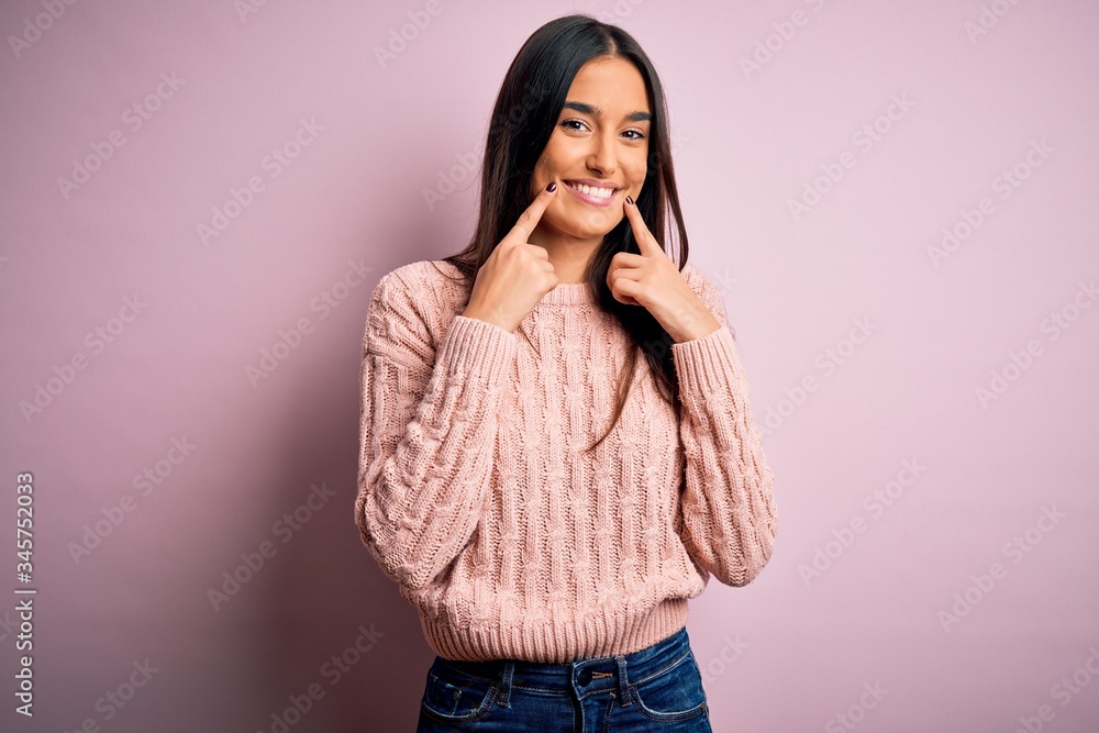 Young beautiful brunette woman wearing casual sweater over isolated pink background Smiling with open mouth, fingers pointing and forcing cheerful smile Young beautiful brunette woman wearing casual sweater over isolated pink background Smiling with open mouth, fingers pointing and forcing cheerful smile