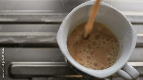 Pouring milk tea in to white cup on metal surface.
