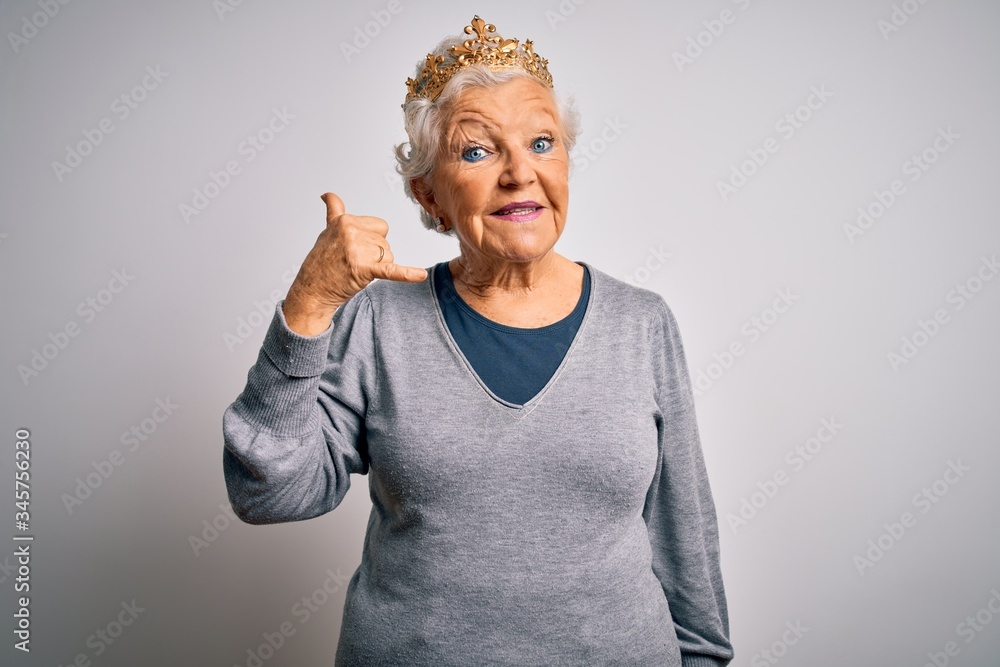 Senior beautiful grey-haired woman wearing golden queen crown over white background smiling doing phone gesture with hand and fingers like talking on the telephone. Communicating concepts. Senior beautiful grey-haired woman wearing golden queen crown over white background smiling doing phone gesture with hand and fingers like talking on the telephone. Communicating concepts.