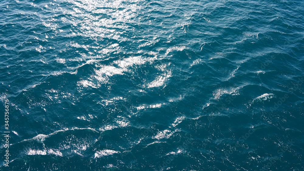 Pure turquoise blue water of the Pacific Ocean. reflection of the sun in the waves on the surface. Natural sea composition, texture, background. aerial view