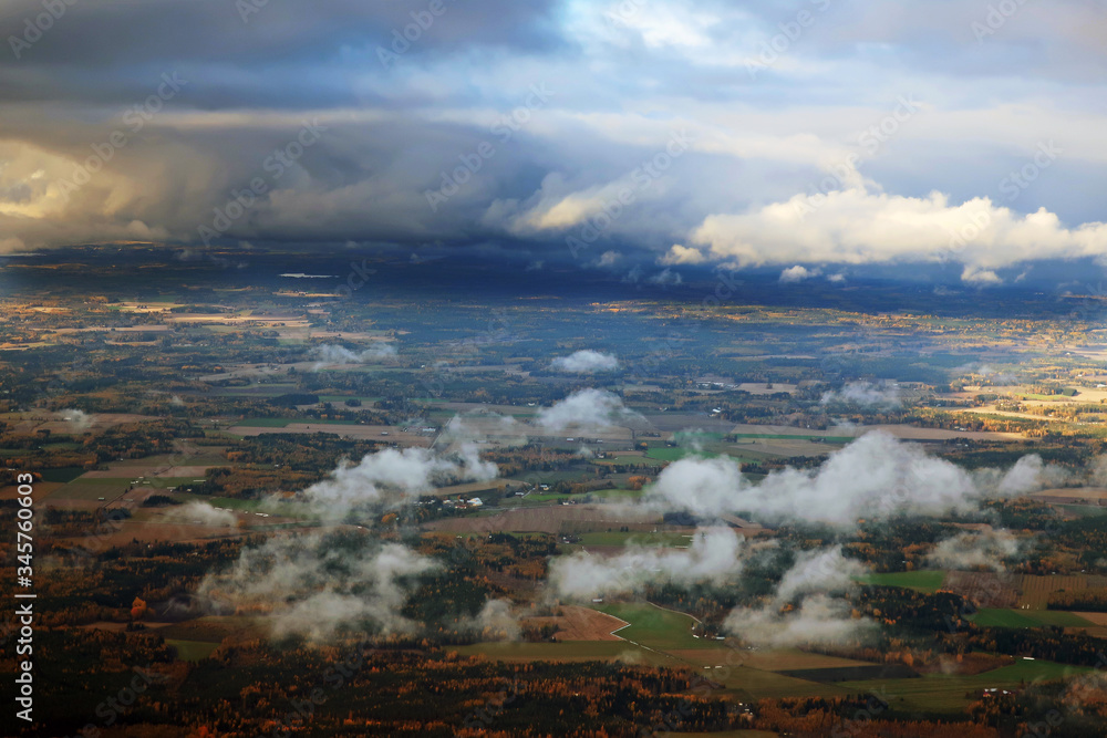 view from above on rare clouds floating over forests and meadows against the backdrop of a beautiful landscape