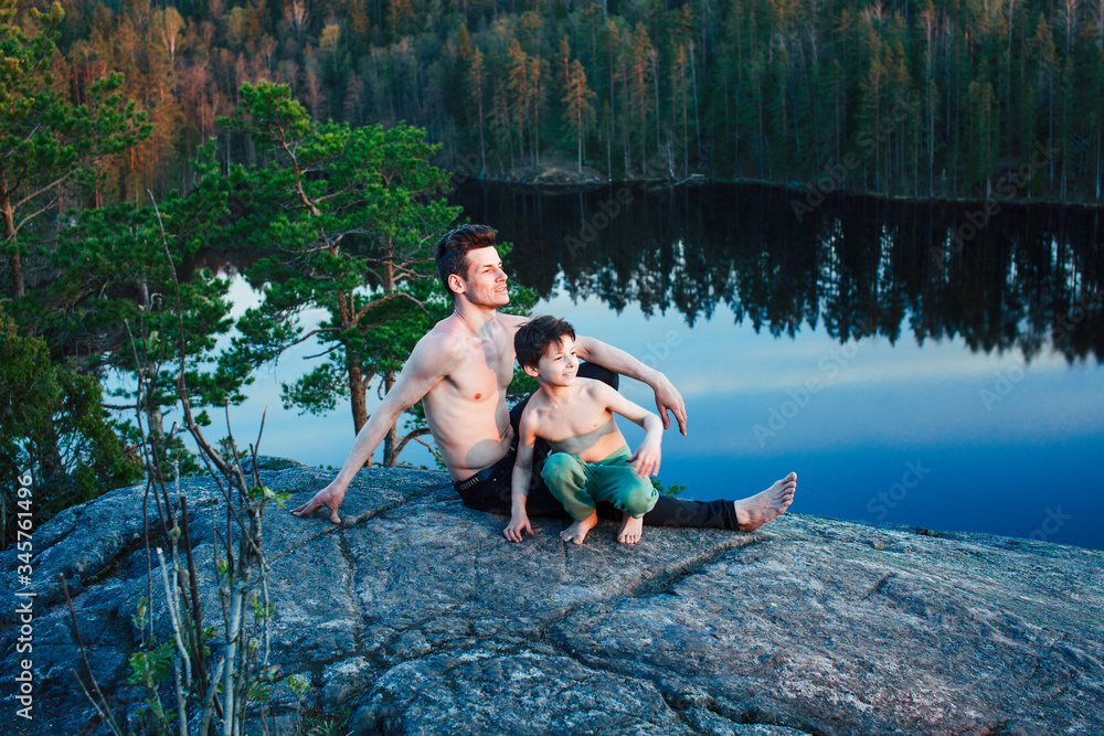 middle age man with little cute son doing sport yoga on the top of the mountain together, happy family lifestyle people outdoor, summer wild nature for training middle age man with little cute son doing sport yoga on the top of the mountain together, happy family lifestyle people outdoor, summer wild nature for training