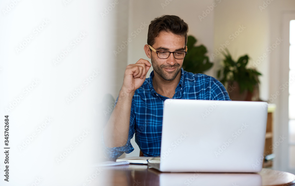 Smiling young man working online with a laptop from home Smiling young man working online with a laptop from home
