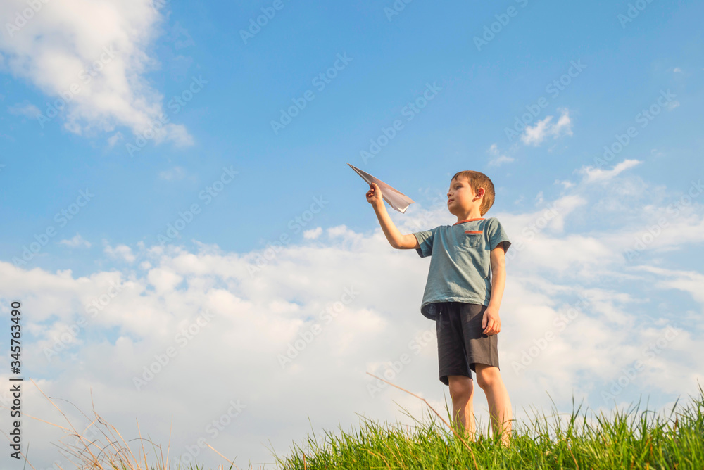 Little boy launches a paper plane into the air. Child launches a paper plane. Happy kid playing with paper airplane Little boy launches a paper plane into the air. Child launches a paper plane. Happy kid playing with paper airplane