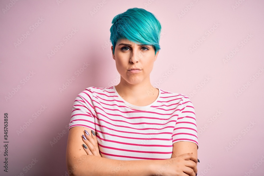 Young beautiful woman with blue fashion hair wearing casual striped t-shirt skeptic and nervous, disapproving expression on face with crossed arms. Negative person. Young beautiful woman with blue fashion hair wearing casual striped t-shirt skeptic and nervous, disapproving expression on face with crossed arms. Negative person.