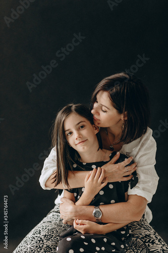 Loving mother and daughter gently hug each other, they smile and enjoy communication. A photo with a blurred background.