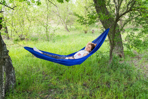 The girl lies in a hammock and relaxes in nature and listening music