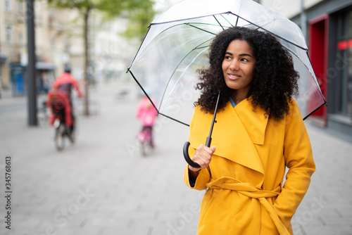 Hübsche lachende Frau mit Regenschirm in der Stadt 
