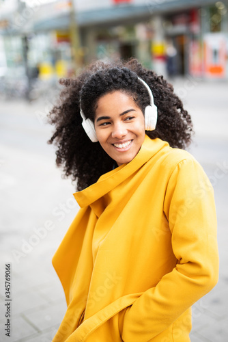 Moderne junge Frau hört Musik über Kopfhörer in urbanem Kontext   © Wellnhofer Designs