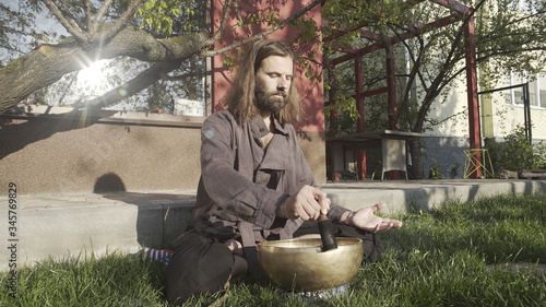 A qigong master conducts meditation using a gong and Crystal bowl, Crystal Tibetian singing bowl, a master meditates receives energy for the body photo