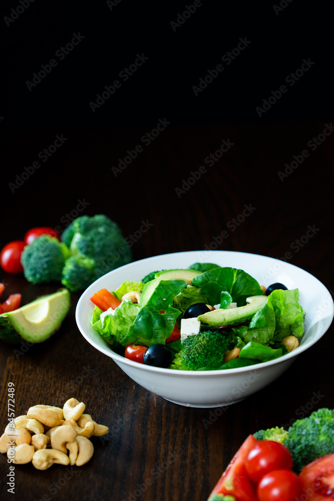 Salad of spinach, avocado, lettuce, tomatoes, broccoli and black olives. Dark photography. Salad of spinach, avocado, lettuce, tomatoes, broccoli and black olives. Dark photography.
