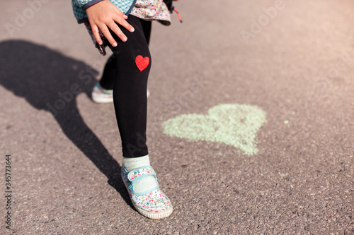 Little girl loves outdoor activitys with red heart sticker on knee. child-health-activity. Kleines Mädchen liebt Bewegung im freien mit rotem Herz Aufnäher auf Hose. Heilende Wirkung. photo