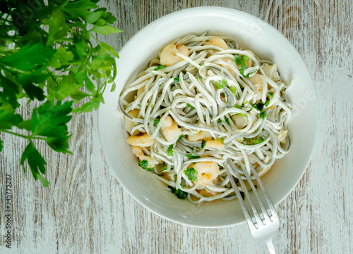 Tableau sur toile Bol blanco de gulas con gambas, ajos, perejil, guindillas sobre mesa blanca