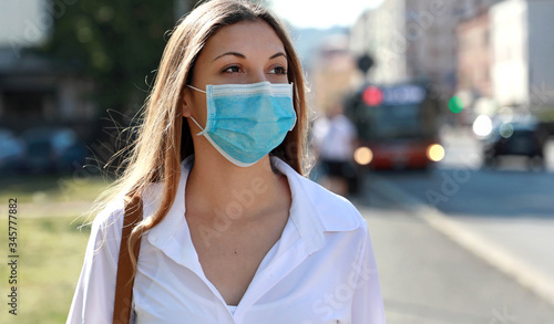 COVID-19 Pandemic Coronavirus Woman in city street wearing surgical mask protective for spreading of disease virus SARS-CoV-2. Girl with protective mask on face against Coronavirus Disease 2019. photo