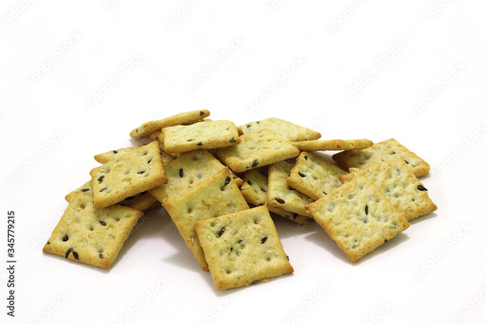 Heap of small square crackers with sesame seeds and flax seeds on a white background. Heap of small square crackers with sesame seeds and flax seeds on a white background.