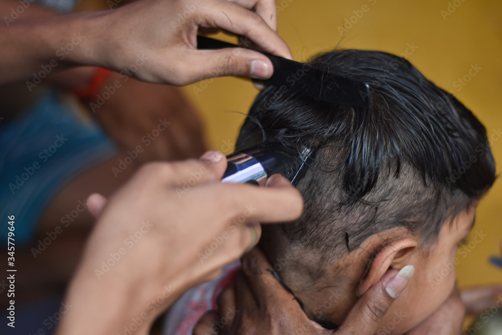 Fototapeta premium after corona virus lockdown every people in quarantine so man cut a boy hair at home with trimmer