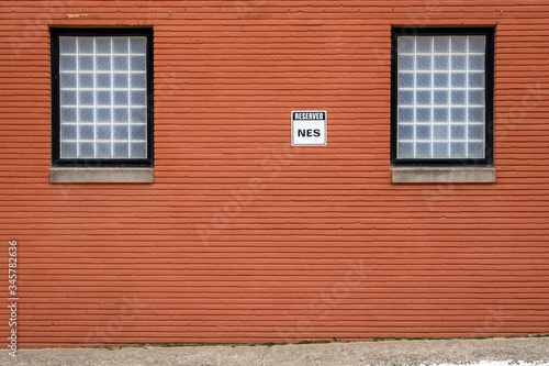 Bright brick wall with windows and a reserved parking sign