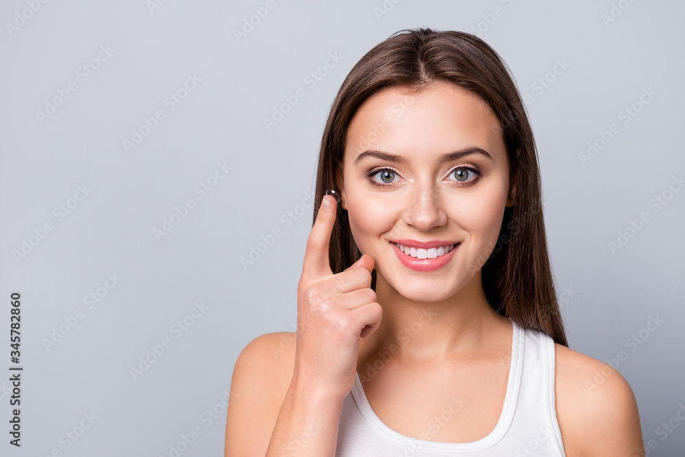 Portrait of positive cheerful girl care eye hold transparent contact lens her oculist prescribe remedy wear white tank-top isolated over gray color background Portrait of positive cheerful girl care eye hold transparent contact lens her oculist prescribe remedy wear white tank-top isolated over gray color background