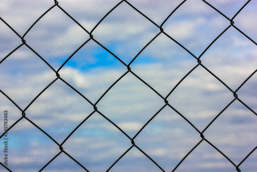 Metal lattice against a blue sky background: freedom or arrest? Metal lattice against a blue sky background: freedom or arrest?