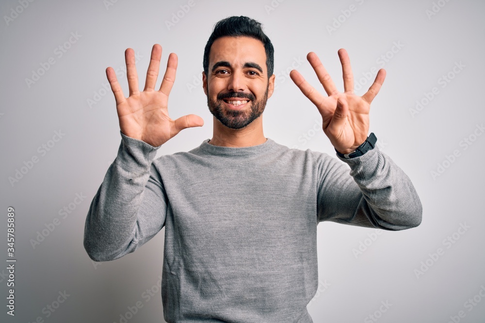 Young handsome man with beard wearing casual sweater standing over white background showing and pointing up with fingers number nine while smiling confident and happy. Young handsome man with beard wearing casual sweater standing over white background showing and pointing up with fingers number nine while smiling confident and happy.