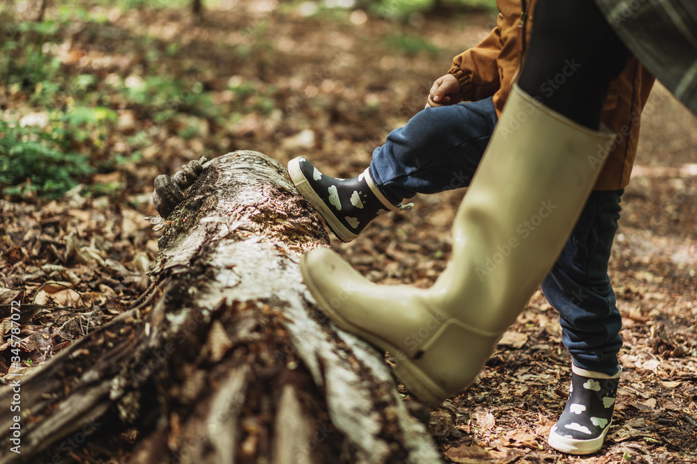 A child with mother standing in rainy boots in leaves A child with mother standing in rainy boots in leaves